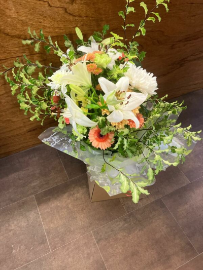 Soft Elegance - A beautifully balanced arrangement that combines soft, calming tones with fresh, natural greenery. Gentle creams and warm peach accents create a light and uplifting feel, while the flowing foliage adds movement and a touch of wild, garden-inspired charm. The mix of textures gives this piece depth and interest, all brought together in a relaxed yet refined design. Perfect for any occasion, it offers a graceful blend of freshness, warmth, and understated elegance.
