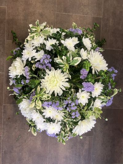 Posy - A soft and elegant funeral posy arrangement featuring calming white and lilac tones nestled amongst fresh variegated foliage. Designed with a natural garden-inspired style, this tribute offers a gentle expression of sympathy, remembrance, and everlasting peace.